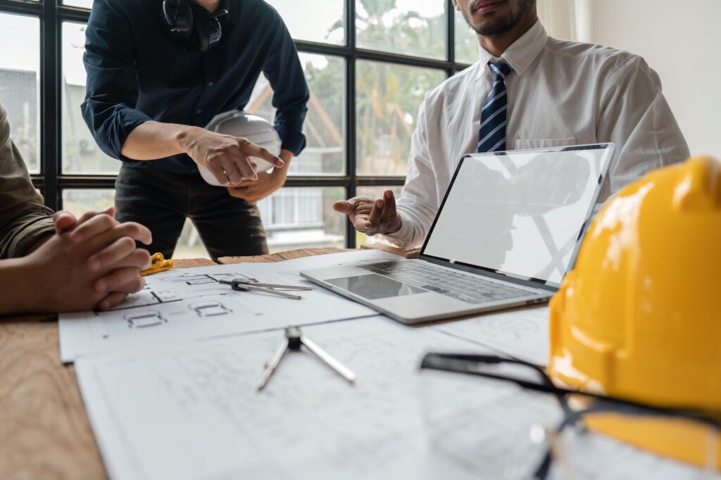 Team of engineers meeting to report project construction on laptop screen